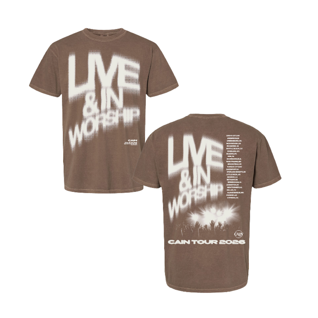 A brown short-sleeve graphic T-shirt shown from both front and back on a plain white background. The front features large white distressed text reading 'LIVE & IN WORSHIP,' and the back has matching large text, smaller white text blocks, and a white crowd silhouette graphic near the hem.